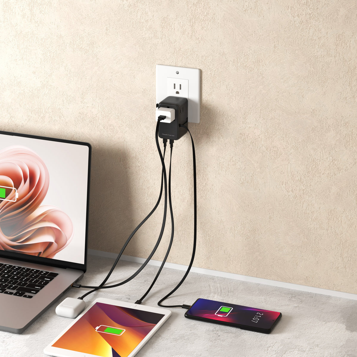 ReelCharge 70W Global Travel Charger plugged into a wall outlet charging a laptop, tablet and phone