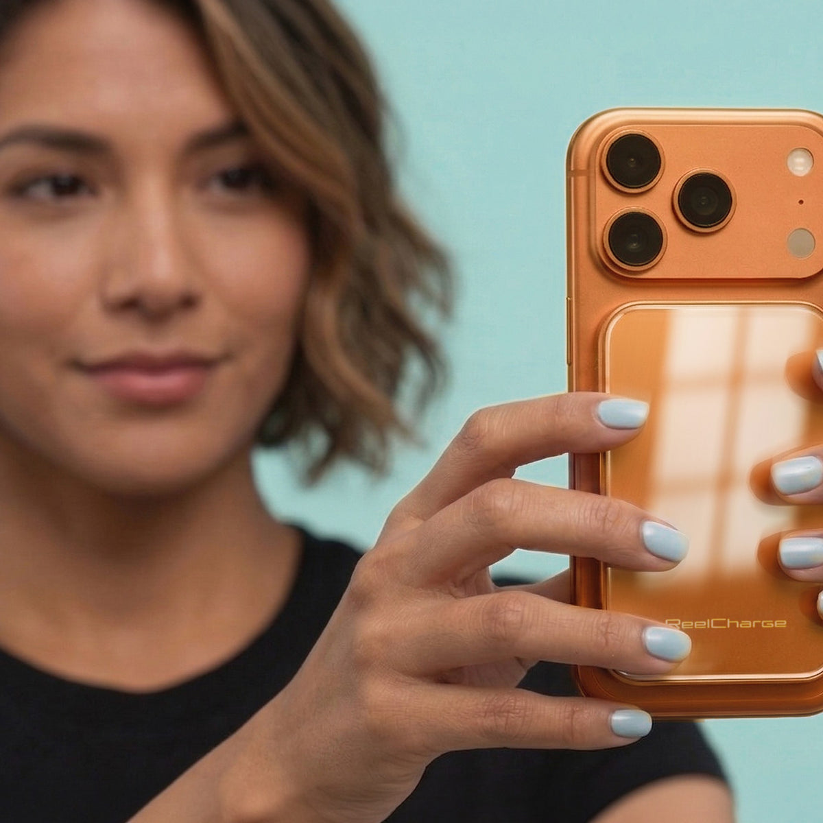 Woman holding a phone with the orange ReelCharge Solid State Premium Wireless Power Bank 5,000 mAh attached magnetically